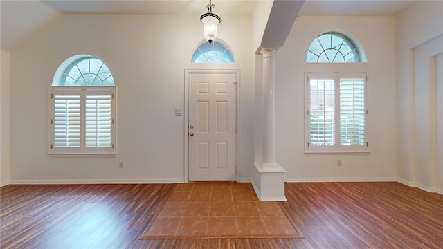 entrance foyer featuring wood-type flooring, vaulted ceiling, and ornate columns