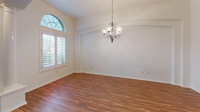 empty room with dark wood-type flooring, a chandelier, and ornate columns