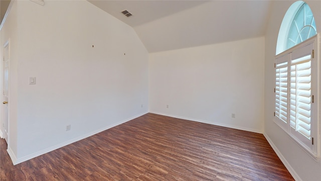 empty room with dark wood-type flooring and lofted ceiling