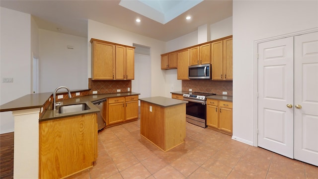 kitchen with sink, a skylight, stainless steel appliances, a center island, and kitchen peninsula