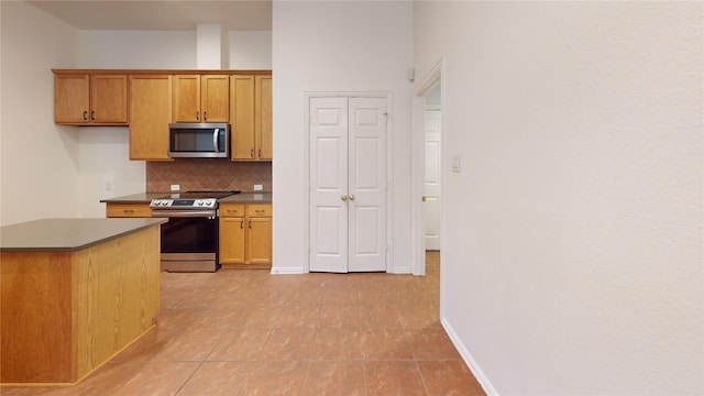 kitchen with appliances with stainless steel finishes, light tile patterned floors, and backsplash