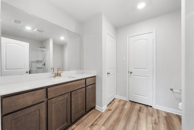 bathroom featuring vanity, wood-type flooring, toilet, and walk in shower