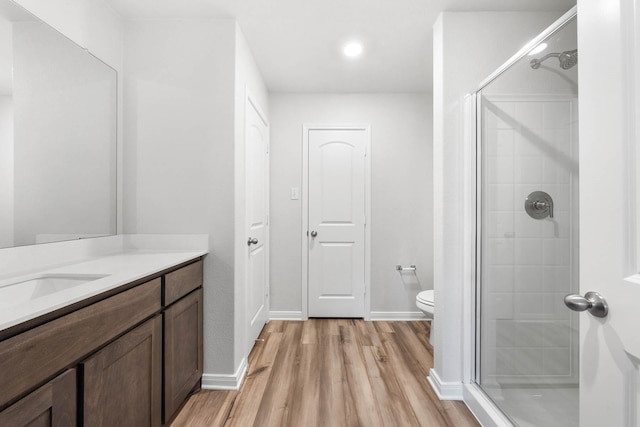 bathroom with walk in shower, vanity, toilet, and hardwood / wood-style floors