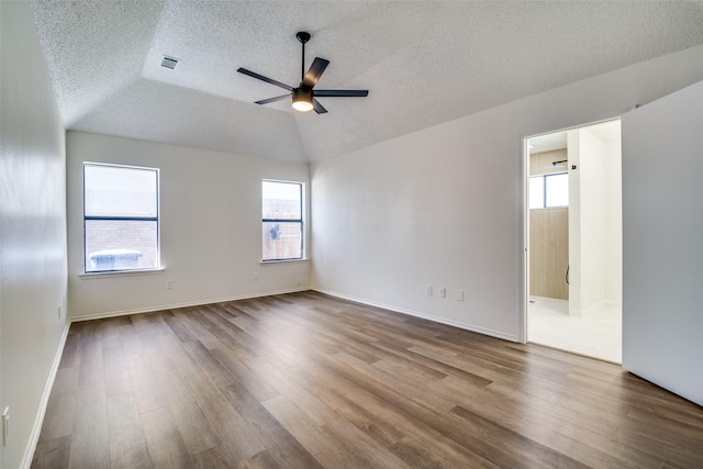 unfurnished room with a textured ceiling, wood-type flooring, ceiling fan, and vaulted ceiling