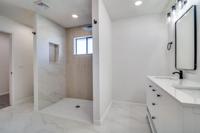 bathroom featuring a tile shower, vanity, and a textured ceiling