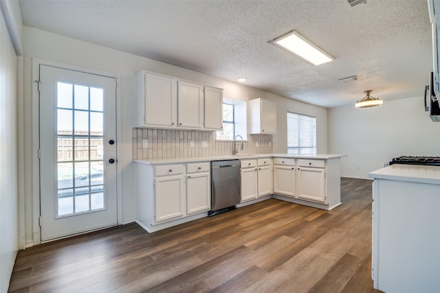 kitchen with dark hardwood / wood-style floors, tasteful backsplash, white cabinets, kitchen peninsula, and stainless steel appliances