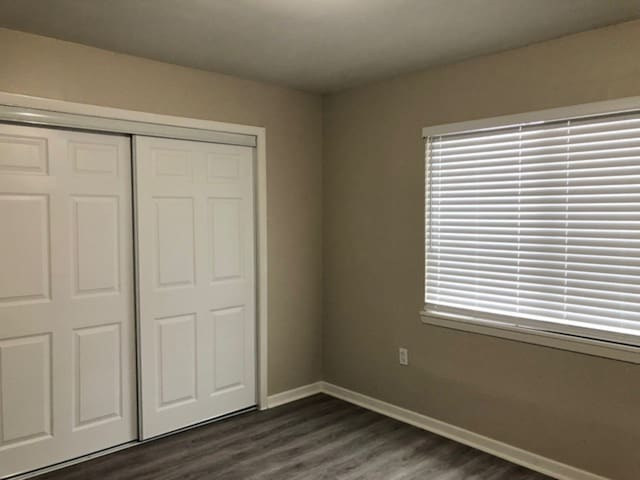 unfurnished bedroom with dark hardwood / wood-style floors and a closet