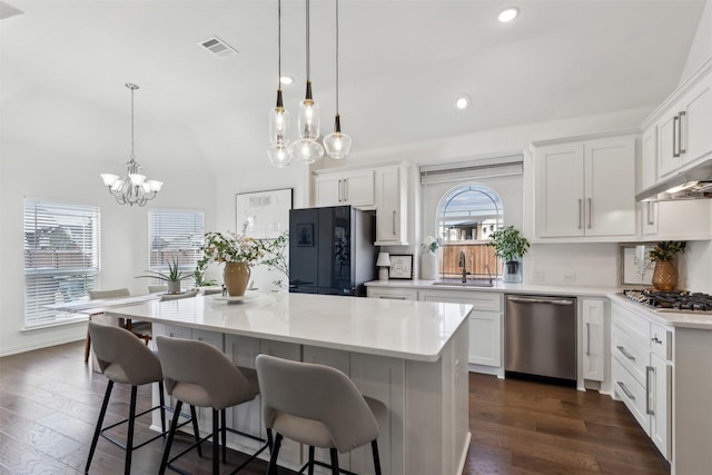 kitchen with sink, white cabinetry, hanging light fixtures, a kitchen island, and stainless steel appliances