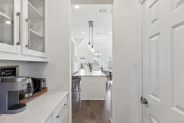 bar featuring white cabinetry, dark hardwood / wood-style floors, decorative light fixtures, and an inviting chandelier