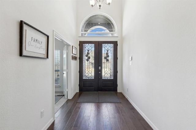 foyer entrance featuring an inviting chandelier, a towering ceiling, and dark hardwood / wood-style floors