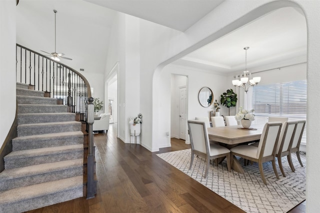 dining area featuring a tray ceiling, dark hardwood / wood-style floors, and ceiling fan with notable chandelier