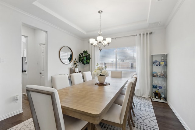 dining area featuring crown molding, a tray ceiling, dark hardwood / wood-style floors, and a chandelier