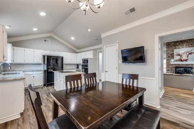 dining room featuring vaulted ceiling, crown molding, sink, and hardwood / wood-style flooring