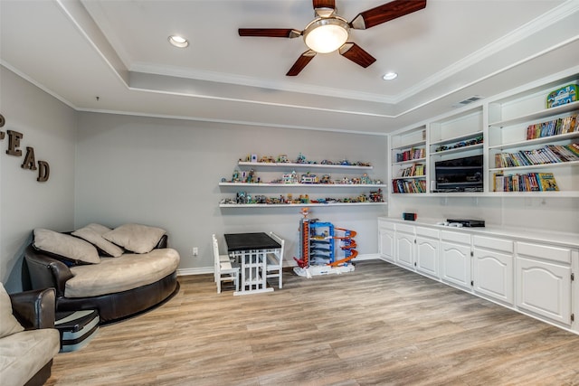 living area featuring crown molding, a raised ceiling, and light hardwood / wood-style floors