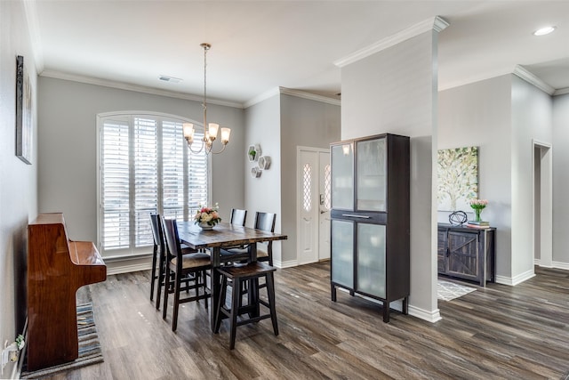 dining area featuring dark wood-type flooring, ornamental molding, and an inviting chandelier