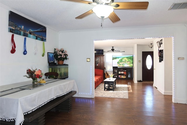 living room with crown molding, ceiling fan, a textured ceiling, and dark hardwood / wood-style flooring