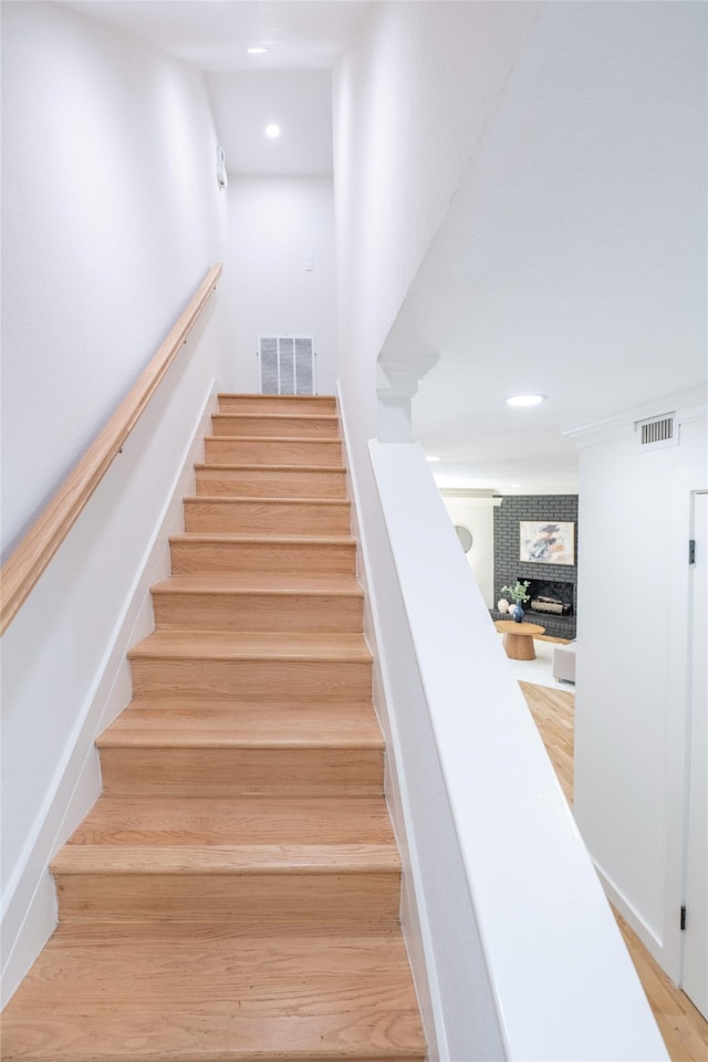 staircase featuring hardwood / wood-style floors and a fireplace