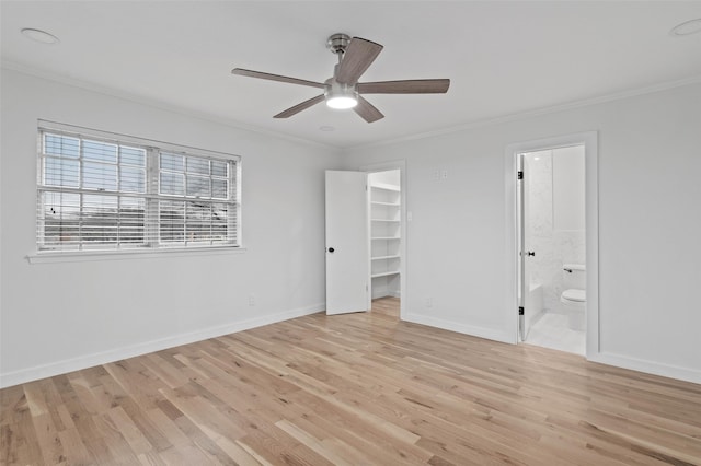 unfurnished bedroom with a walk in closet, crown molding, light hardwood / wood-style flooring, and ensuite bath