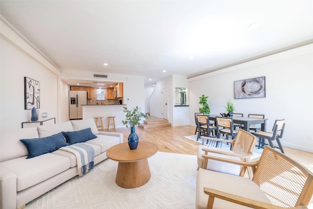 living room with crown molding and light hardwood / wood-style floors