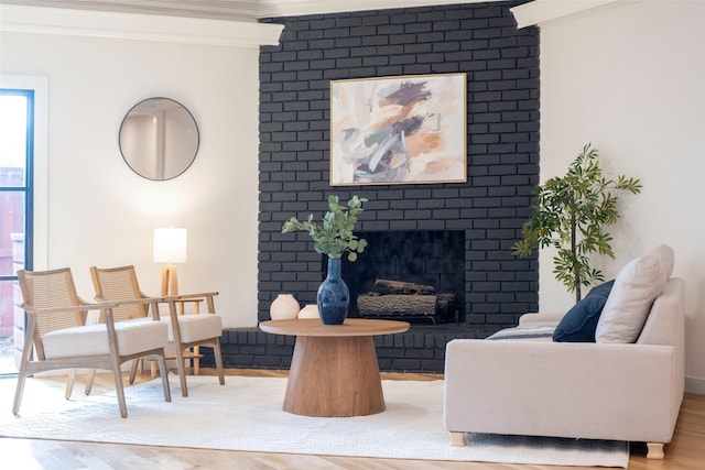 living room featuring ornamental molding, a brick fireplace, and light hardwood / wood-style floors