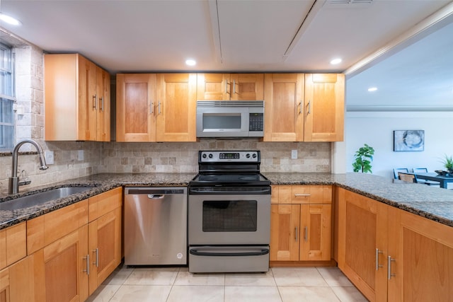 kitchen featuring appliances with stainless steel finishes, tasteful backsplash, sink, dark stone counters, and light tile patterned floors