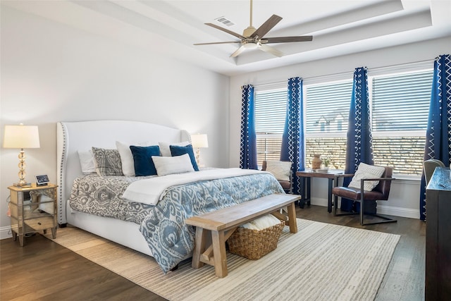 bedroom with hardwood / wood-style floors, ceiling fan, and a tray ceiling