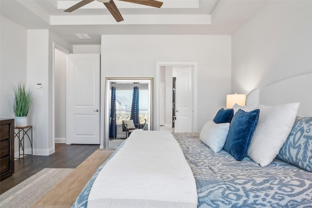 bedroom featuring dark hardwood / wood-style flooring, a tray ceiling, and ceiling fan