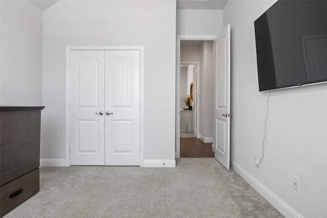 unfurnished bedroom featuring light carpet and a closet