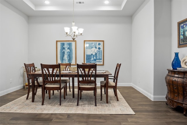 dining room with a raised ceiling, dark hardwood / wood-style floors, and a chandelier