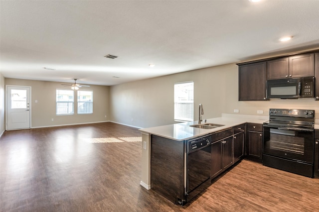 kitchen with sink, kitchen peninsula, dark hardwood / wood-style flooring, and black appliances