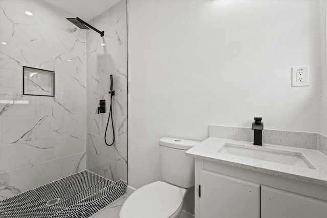 bathroom with vanity, tiled shower, and toilet