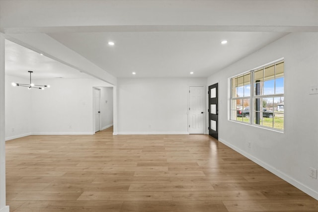 empty room featuring an inviting chandelier and light hardwood / wood-style floors