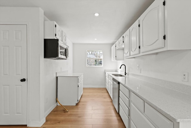 kitchen featuring sink, white cabinetry, stainless steel appliances, light stone countertops, and light wood-type flooring