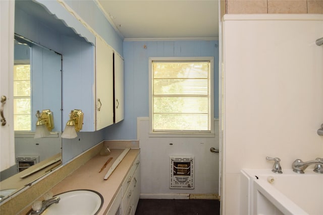 bathroom featuring crown molding, vanity, heating unit, and a tub