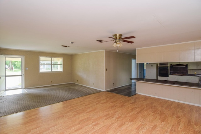 unfurnished living room featuring ornamental molding, ceiling fan, and light wood-type flooring