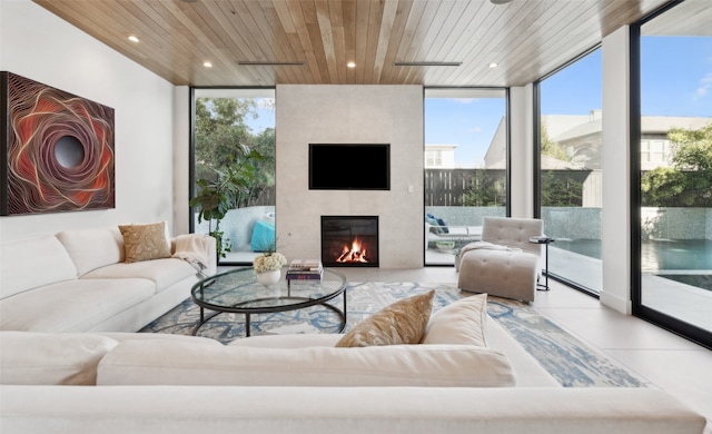 tiled living room with a tiled fireplace, a wealth of natural light, a wall of windows, and wooden ceiling