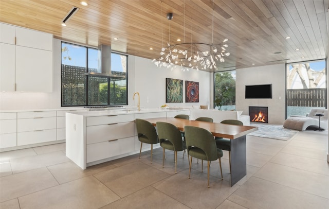 dining area with wood ceiling, a large fireplace, a healthy amount of sunlight, and light tile patterned floors