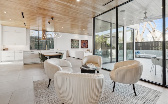 living room featuring ceiling fan with notable chandelier, wooden ceiling, expansive windows, and light tile patterned flooring