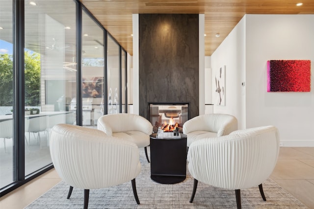 sitting room with expansive windows, a multi sided fireplace, wooden ceiling, and light tile patterned floors