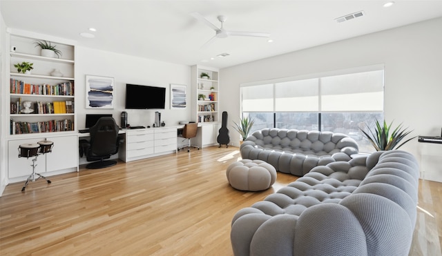 living room featuring ceiling fan, built in desk, built in features, and light wood-type flooring