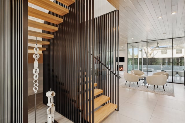 stairs with a fireplace, tile patterned floors, floor to ceiling windows, and wooden ceiling