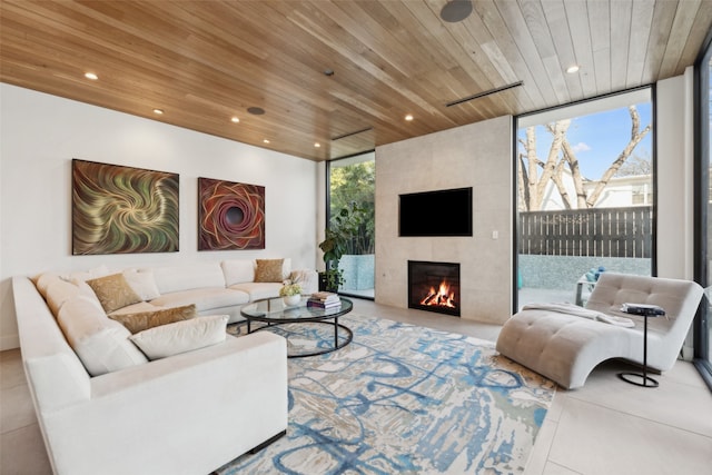 tiled living room with a tiled fireplace, wood ceiling, and floor to ceiling windows