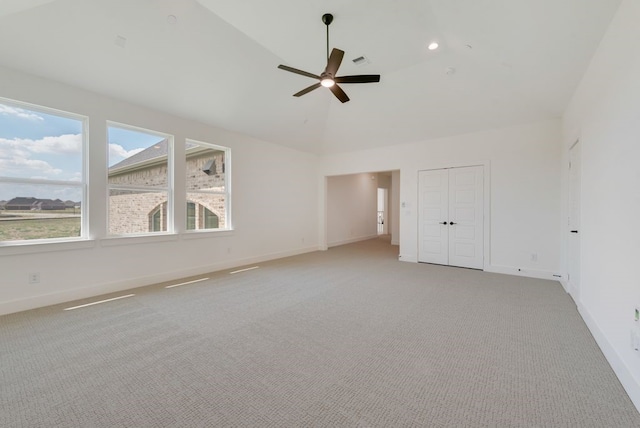 empty room with high vaulted ceiling, light colored carpet, and ceiling fan