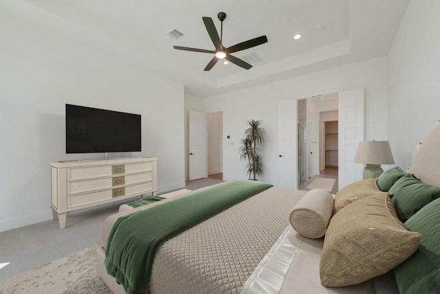 carpeted bedroom with ceiling fan and a raised ceiling