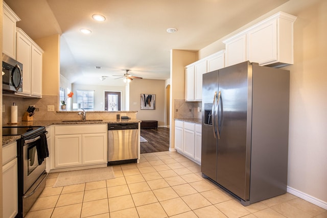 kitchen with sink, white cabinetry, dark stone counters, kitchen peninsula, and stainless steel appliances