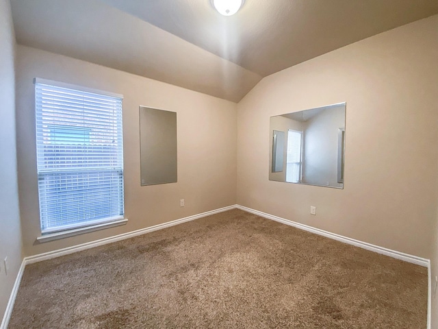 carpeted spare room with vaulted ceiling