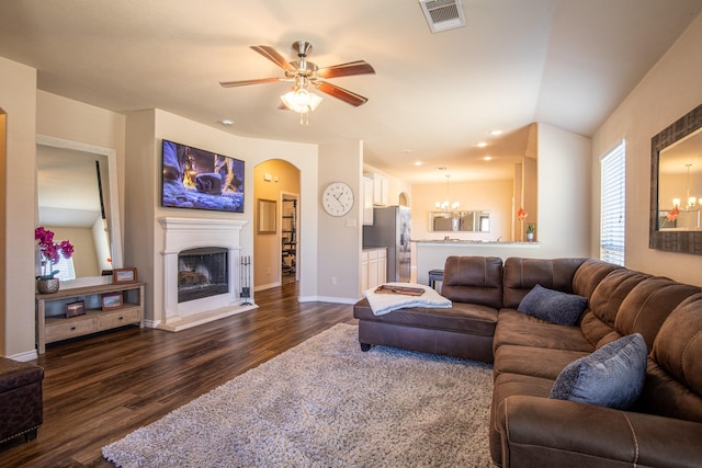 living room featuring ceiling fan with notable chandelier and dark wood-type flooring