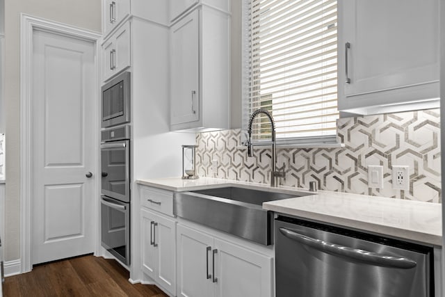 kitchen with sink, appliances with stainless steel finishes, backsplash, dark hardwood / wood-style floors, and white cabinets