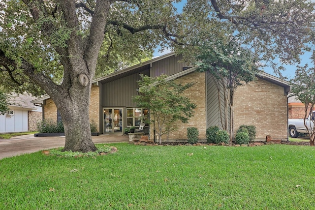 view of front of house with driveway, a front lawn, and brick siding