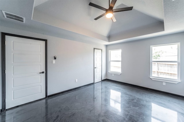 spare room with vaulted ceiling, a raised ceiling, and ceiling fan